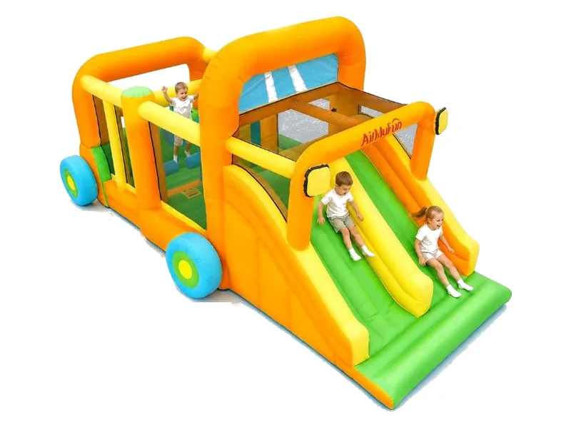 AirMyFun race-car obstacle bounce house in orange and yellow with blue wheels and a double green slide, two children sliding
